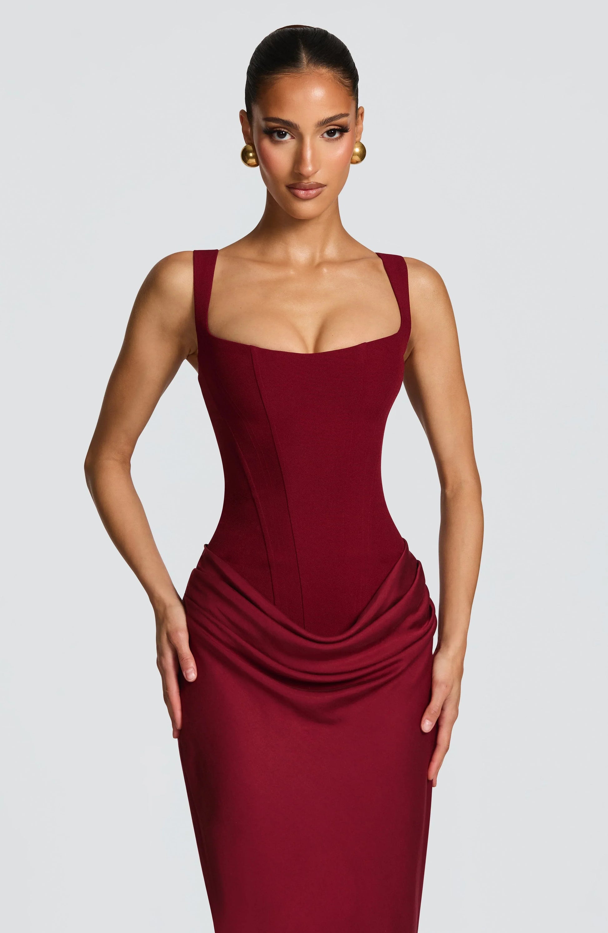 Woman wearing a burgundy dress against a plain background