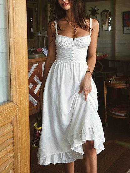 Woman wearing a white dress standing in a room with wooden furniture.