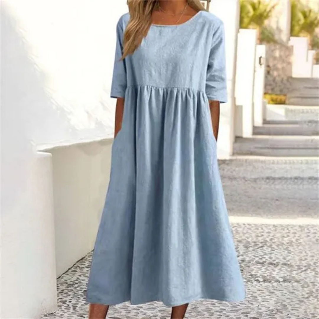 Woman wearing a light blue dress standing on a stone path.