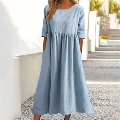 Woman wearing a light blue dress standing on a stone path.