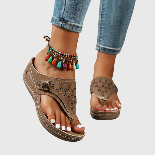 Brown sandals with decorative anklets on a neutral background