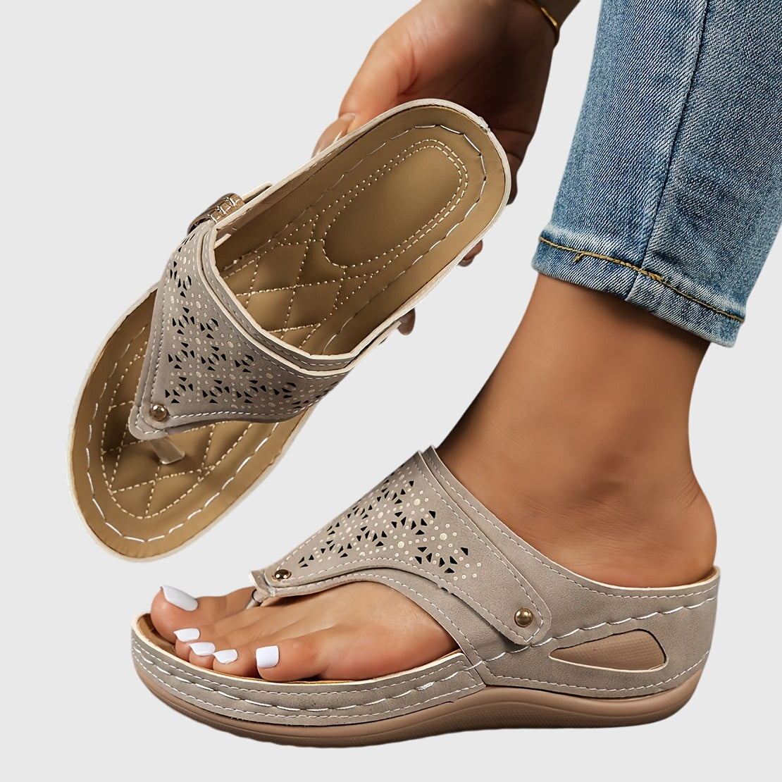 Beige sandals worn with rolled-up jeans on a light gray background