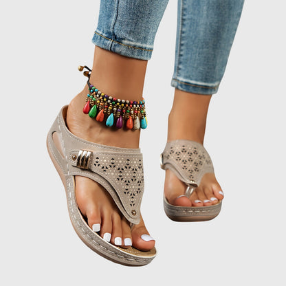 Beige sandals with decorative anklets on a neutral background