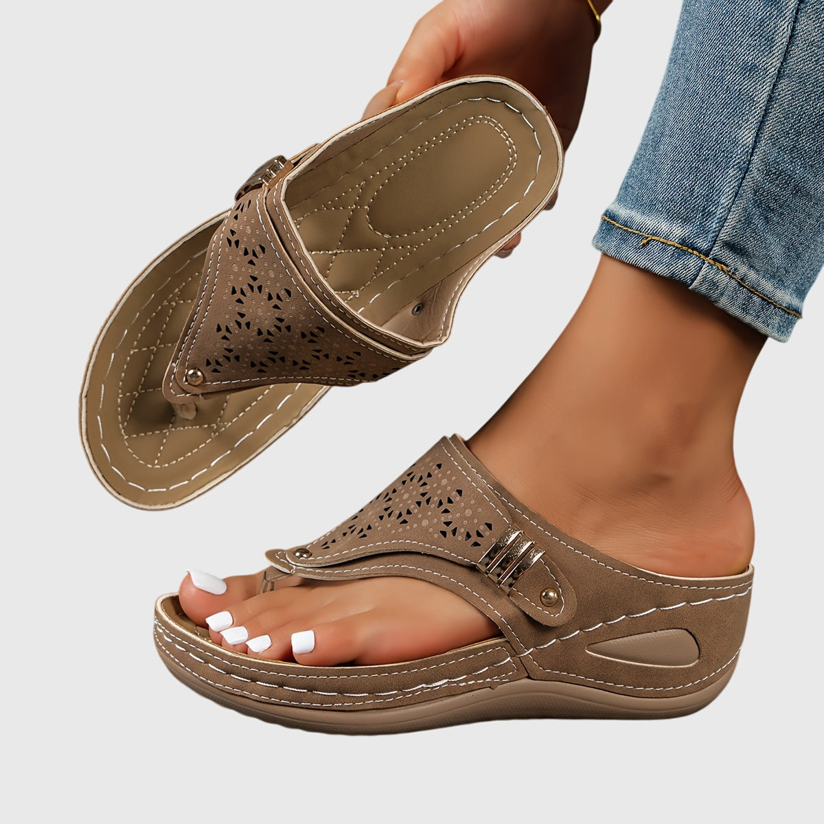 Brown sandal worn on a foot with a light gray background