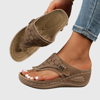 Brown sandal worn on a foot with a light gray background