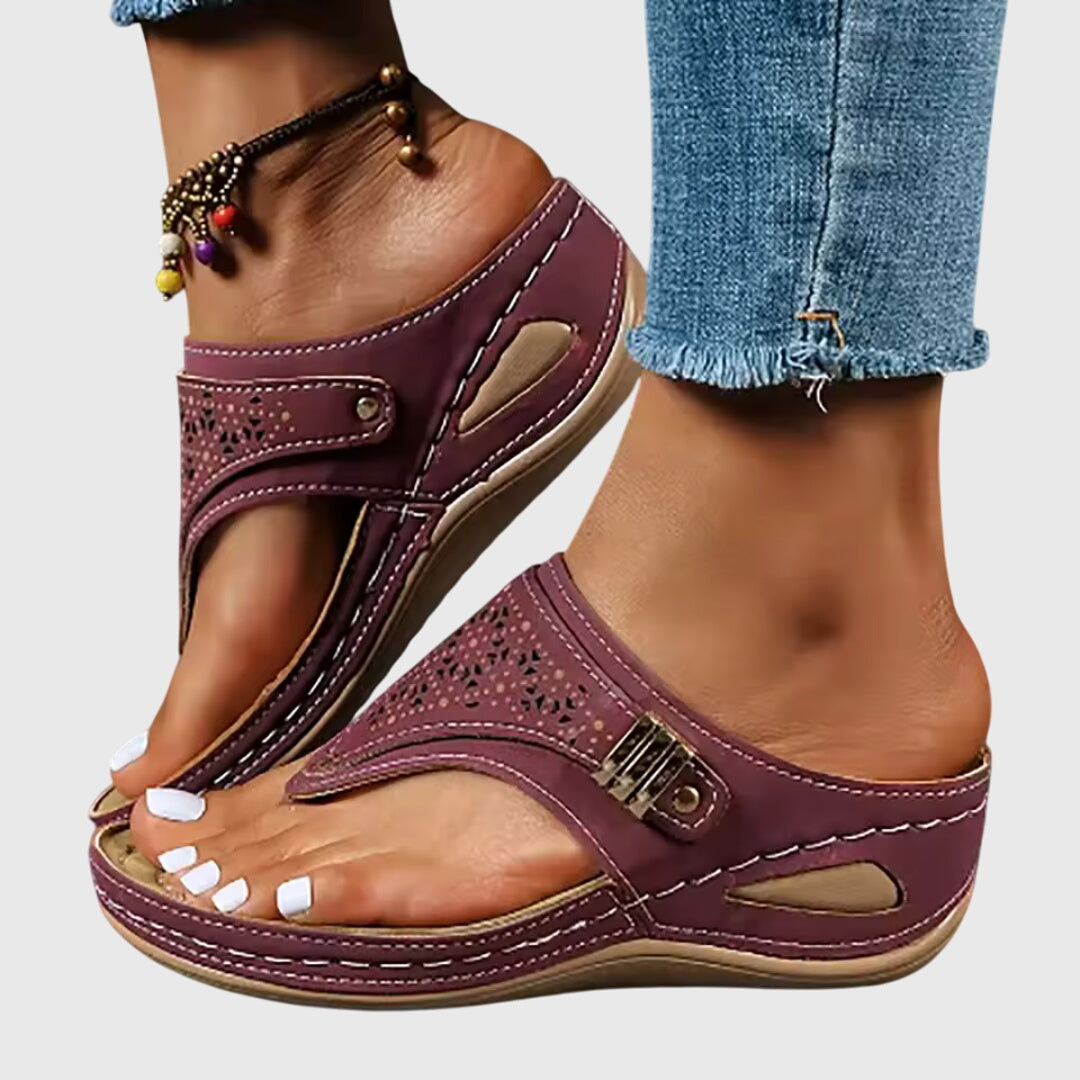 Purple sandals worn with rolled-up jeans on a neutral background