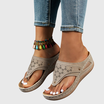 Beige sandals worn with rolled-up jeans on a neutral background