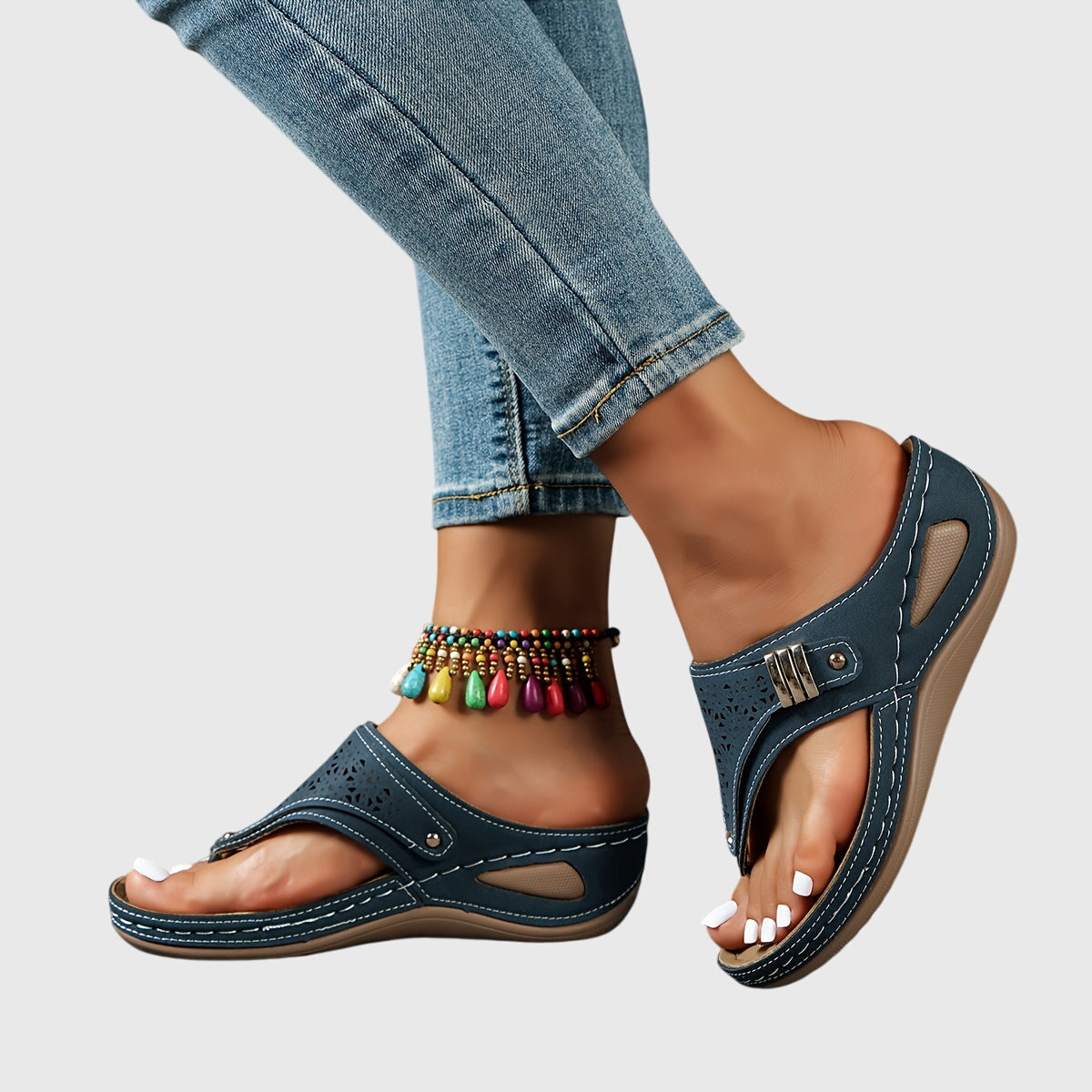 Navy sandals worn with rolled-up jeans on a light gray background