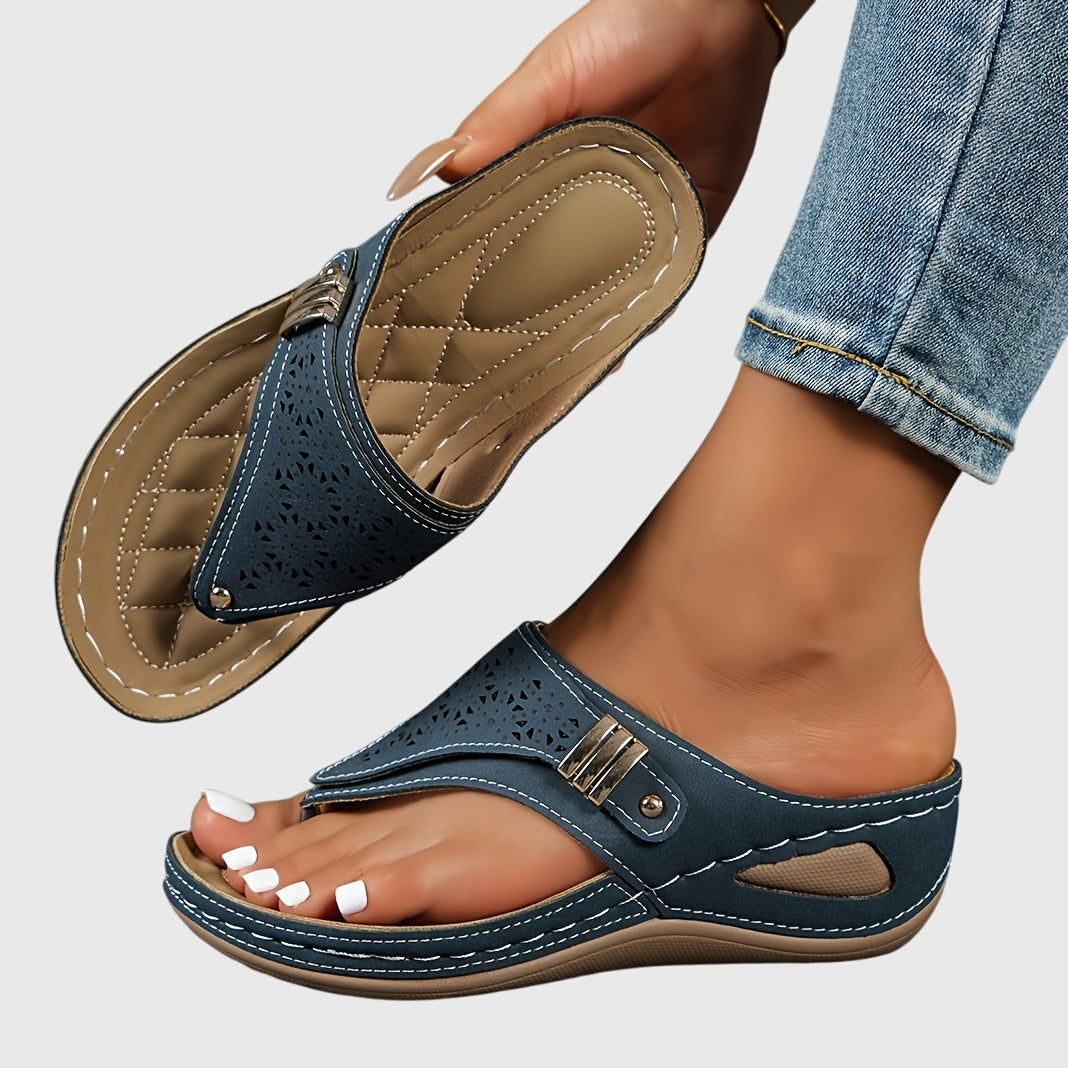 Blue sandals with beige soles worn by a person on a light gray background