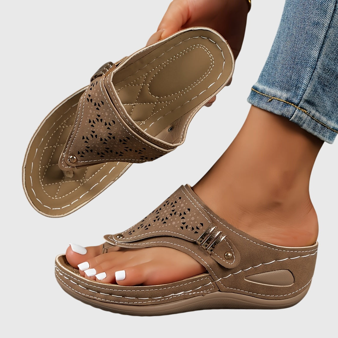 Beige sandal worn with rolled-up jeans on a light gray background