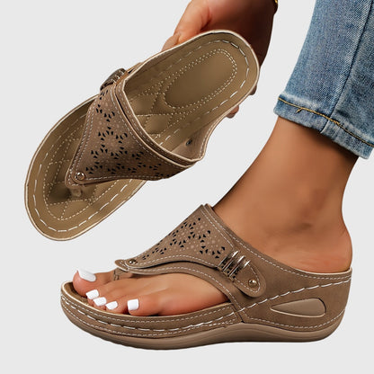 Beige sandal worn with rolled-up jeans on a light gray background
