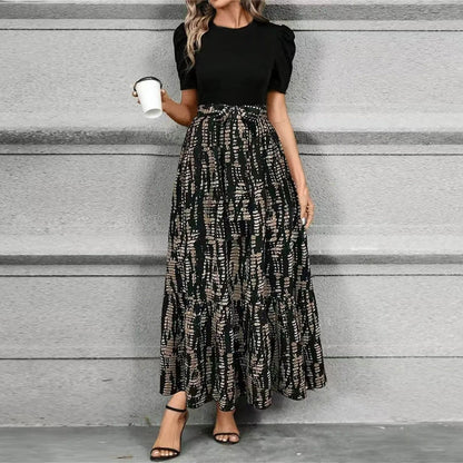 Woman wearing a black top and patterned skirt against a gray background