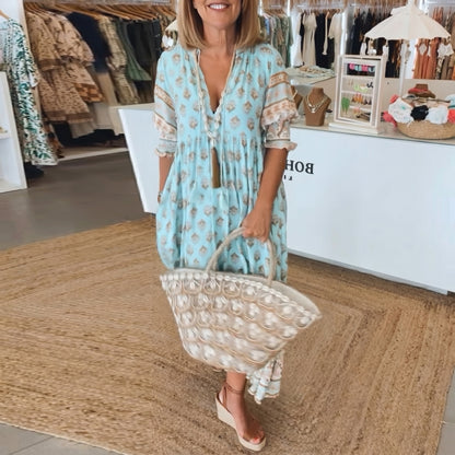 Woman in a light blue dress holding a beige bag in a store setting