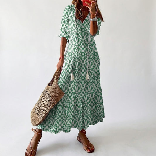 Woman wearing a green patterned dress holding a woven bag against a white background
