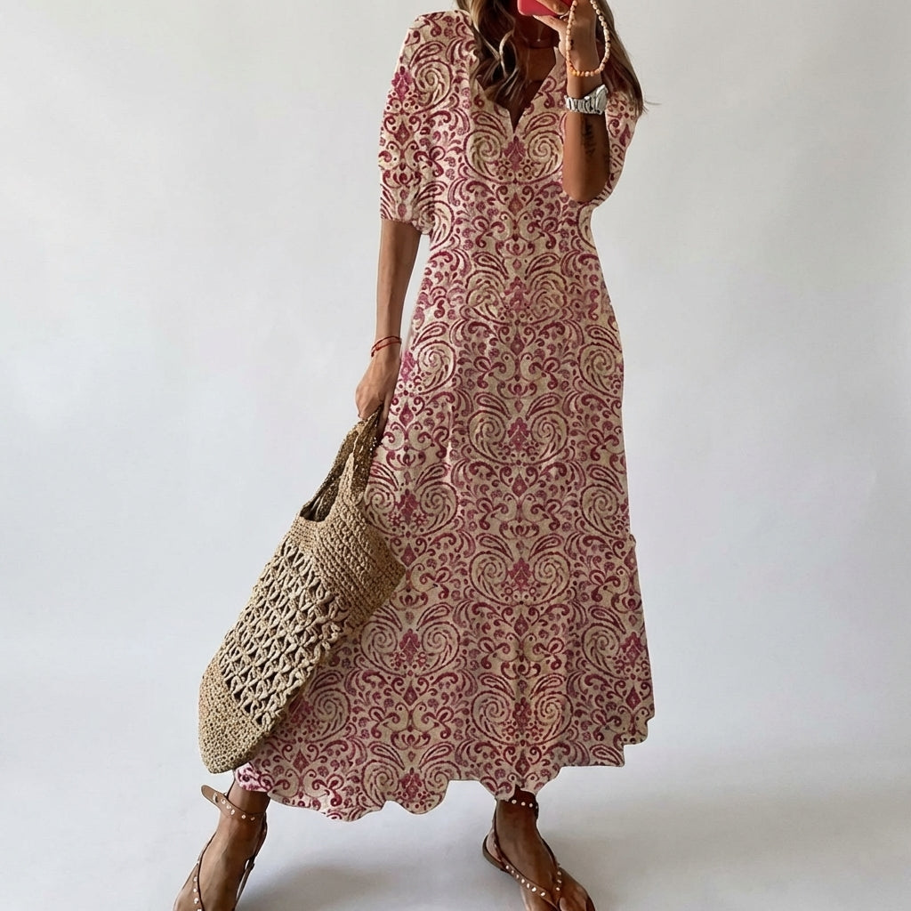 Woman wearing a pink patterned dress holding a woven bag against a white background