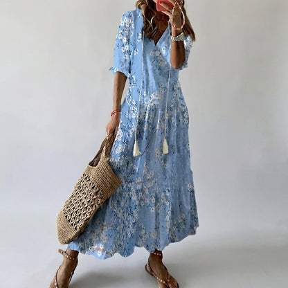 Person wearing a blue floral dress holding a woven bag against a plain background