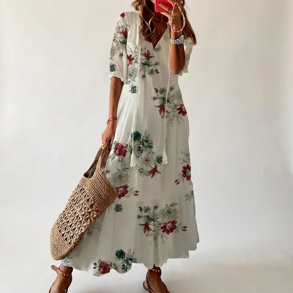 Woman wearing a floral dress holding a woven bag against a plain background