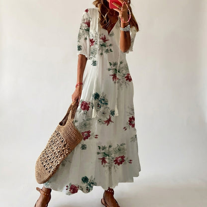 Woman wearing a floral dress holding a woven bag against a plain background