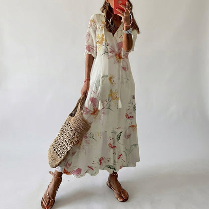 Woman wearing a floral dress holding a woven bag against a plain background