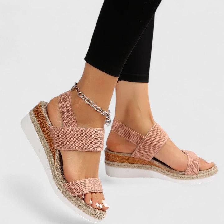 Pink sandals with wooden soles worn by a person on a white background