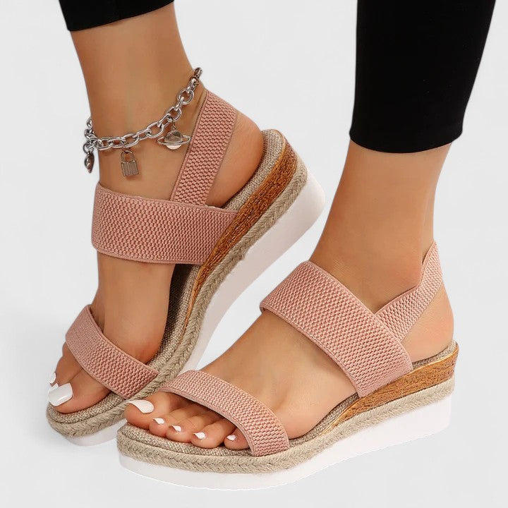 Pink sandals with woven soles worn by a person on a white background