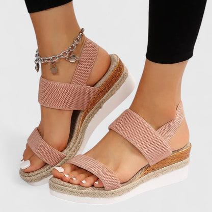 Pink sandals with woven soles worn by a person on a white background