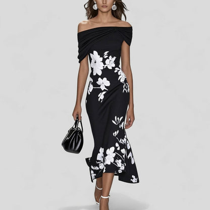 Woman wearing a black off-shoulder dress with white floral patterns on a gray background