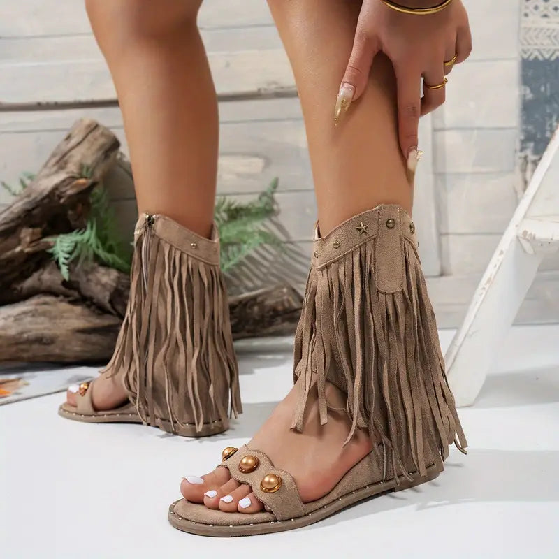 Beige fringe sandals worn by a person with a neutral background