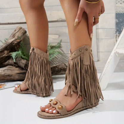 Beige fringe sandals worn by a person with a neutral background