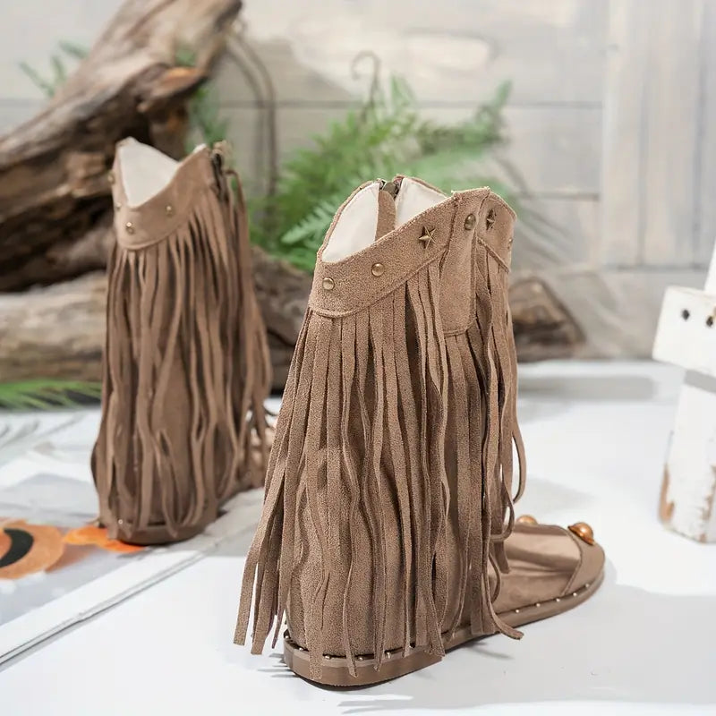 Pair of brown fringe boots on a white surface with a natural background